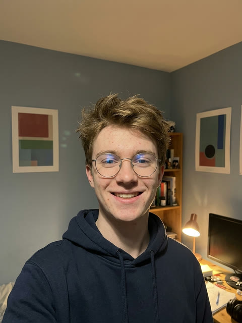 The single photo used: a smiling selfie of a young man in round glasses and a navy hoodie in his bedroom (AI-generated person)