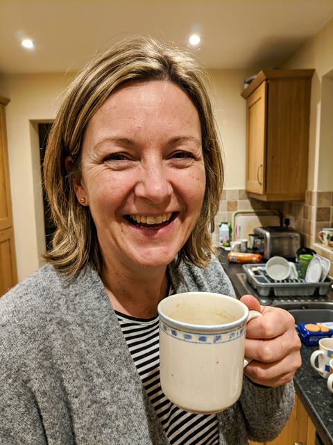 The single photo used: a laughing kitchen photo of a mum in a grey cardigan holding a mug of tea (AI-generated person)